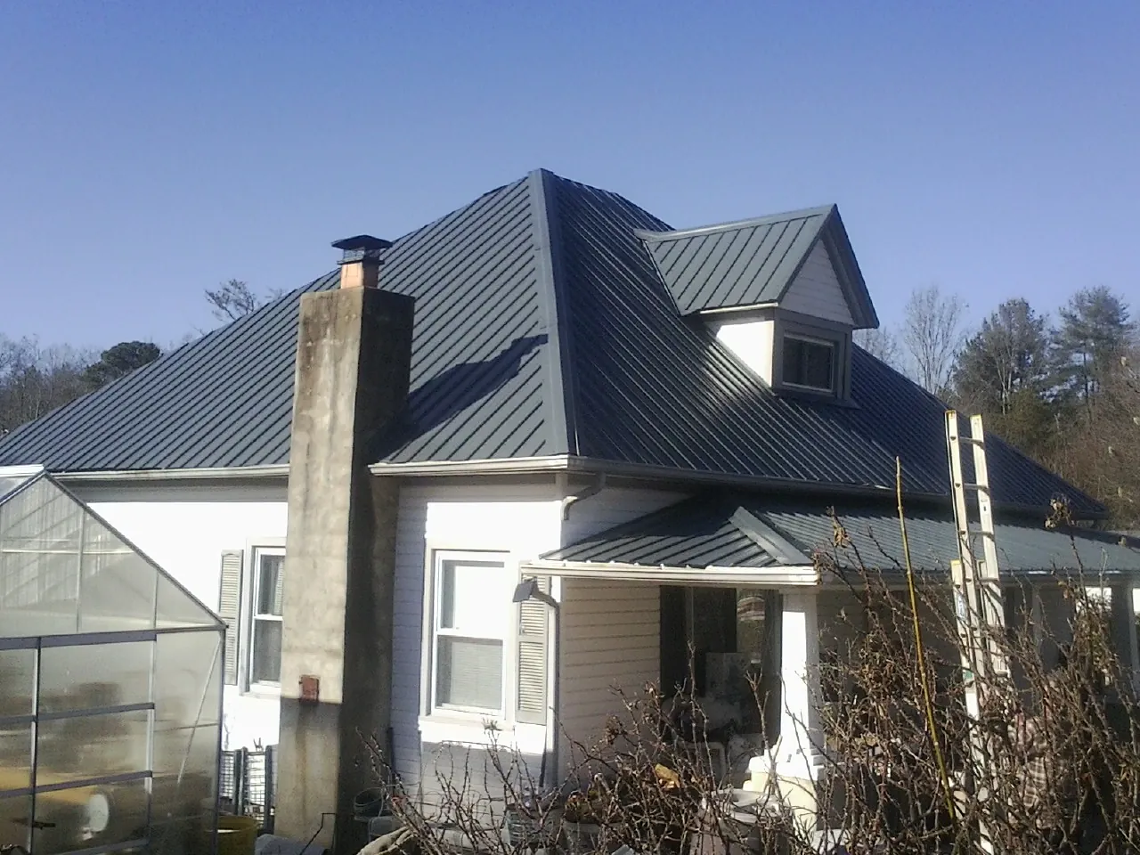 Dark blue standing seam metal roof on a white farmhouse with dormer — Slate & Tile Roof Repair by Roofing Brothers in Orinda