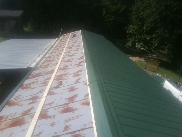 Old rusted panels beside newly installed green metal roofing — Wind Damage Roof Repair by Roofing Brothers in Orinda