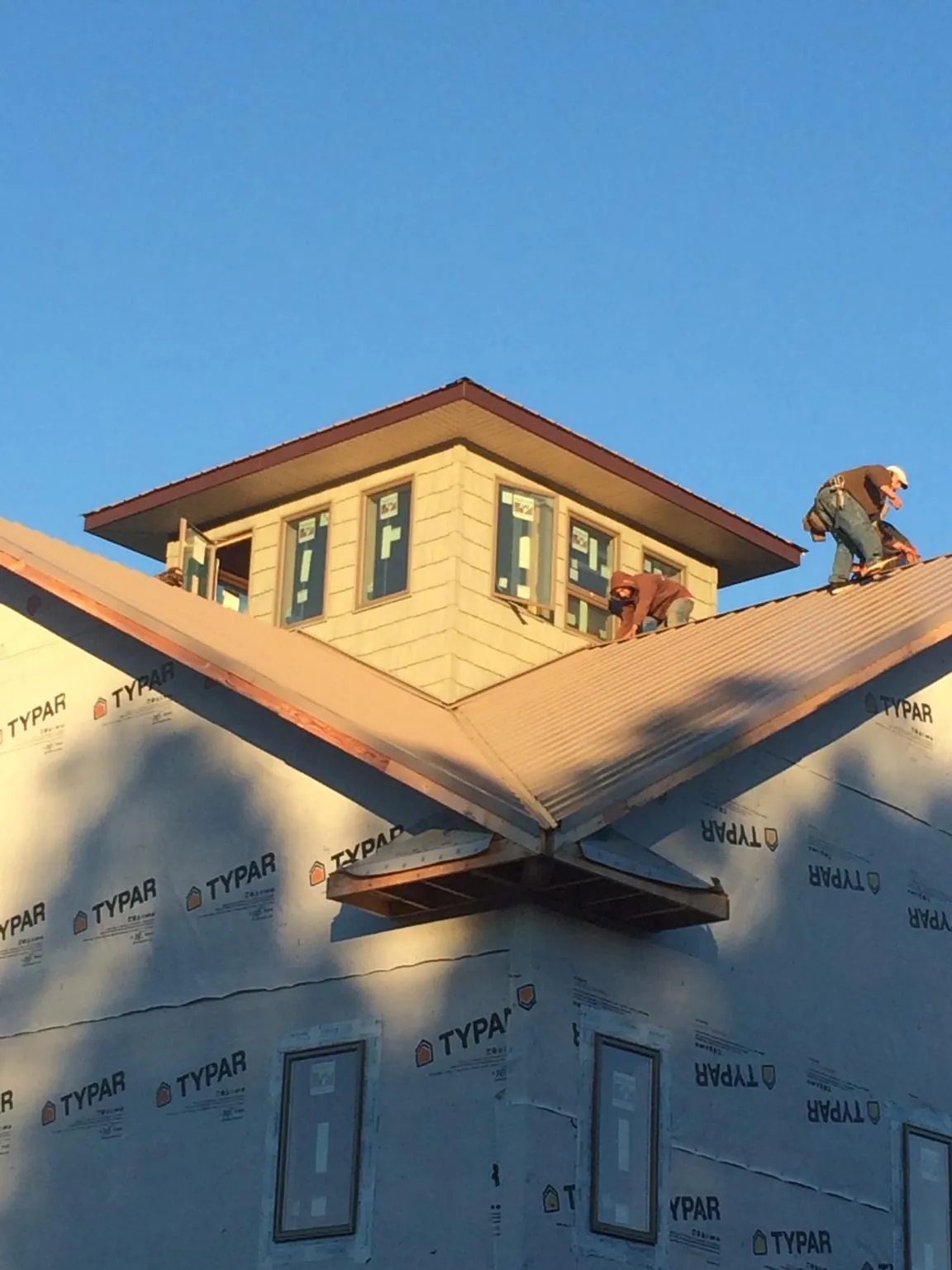 Roofers working around a rooftop cupola on a new metal roof at sunset — Roof Waterproofing in Orinda by Roofing Brothers